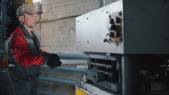 Professional Caucasian Engineer Works with a Sheet of Metal on a Machine Tool