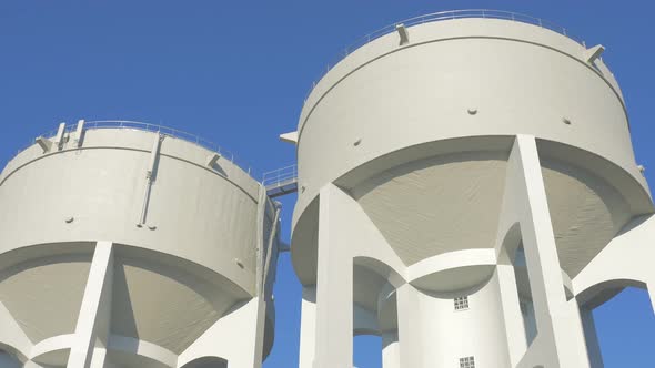 Concrete water towers in front of blue sky slow motion 4K 2160p UHD footage - Water tower made of co alt