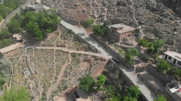 Aerial View Of Car Travelling Through Road In Village Hillside In Kalash Valley In Pakistan. Follow alt