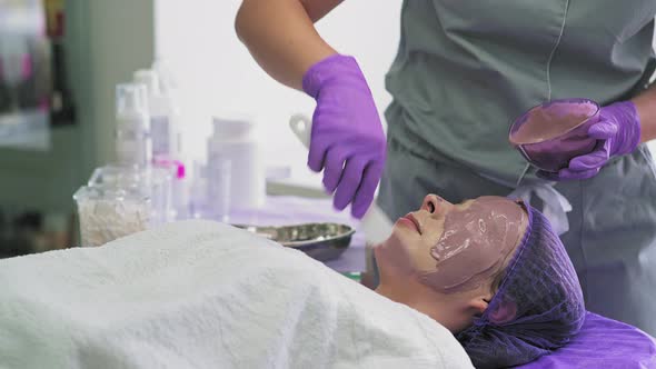 Cosmetologist Applying Facial Mask to the Face alt