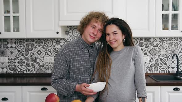 Couple Standing Together in Contemporary Kitchen and Looking at Camera with Nice Smiles alt