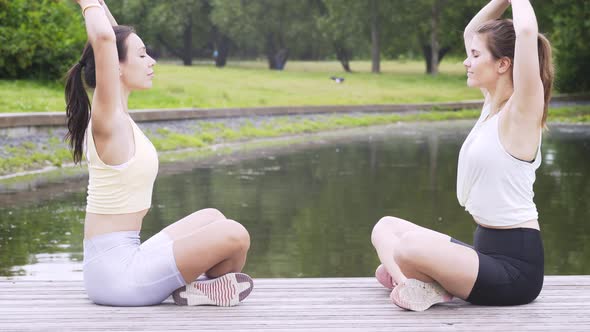 Tranquil Women Do Yoga Exercises Sitting on Wooden Pier
