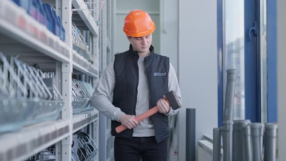 Cheerful Male Worker in Hard Hat Posing with Big Hammer in Hardware Store alt