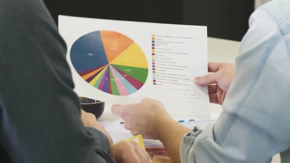 Cropped Shot of Two Businessmen Discussing Printed Diagram alt