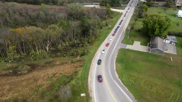 Aerial view of rural trunk highway with parade of corvettes leading to highway in Wisconsin.