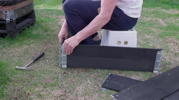 Close up view of man collecting collar of pallet for planting vegetable seeds in it. Sweden. alt