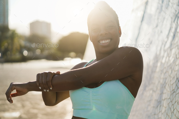 Happy african woman doing sport stretching exercise outdoor - Soft focus on right hand