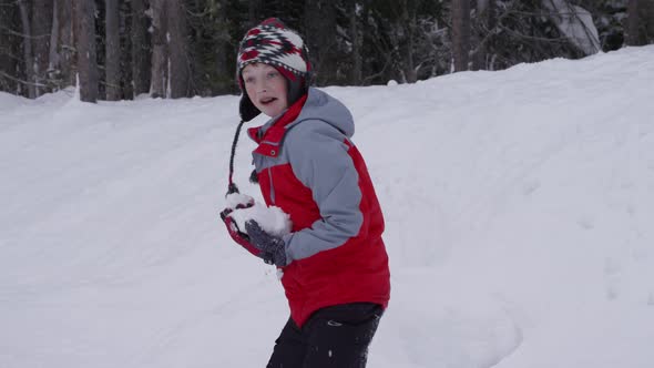 Boy throwing snowballs in slow motion alt