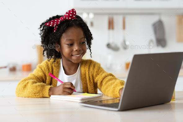 Cute Preteen Black Girl Writing In Notepad While Study Online With Laptop