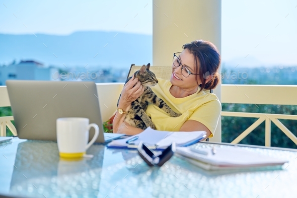 Home workplace female freelancer working remotely with pet cat in her arms