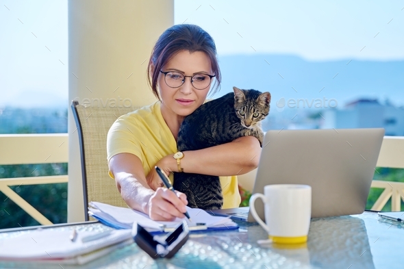 Home workplace female freelancer working remotely with pet cat in her arms
