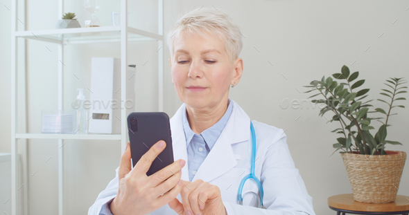 Senior doctor using smartphone and remote telehealth medical app - Stock Photo - Images