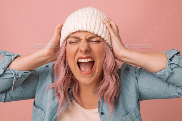 Closeup portrait of young emotion angry woman screaming on pink background