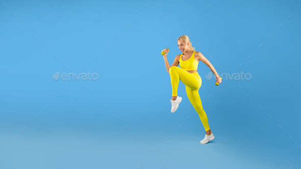 Young Woman Exercising With Dumbbells Isolated On Blue Background