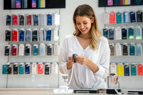 Shopping a new digital device. Happy beautiful woman choosing a smart watch in tech store