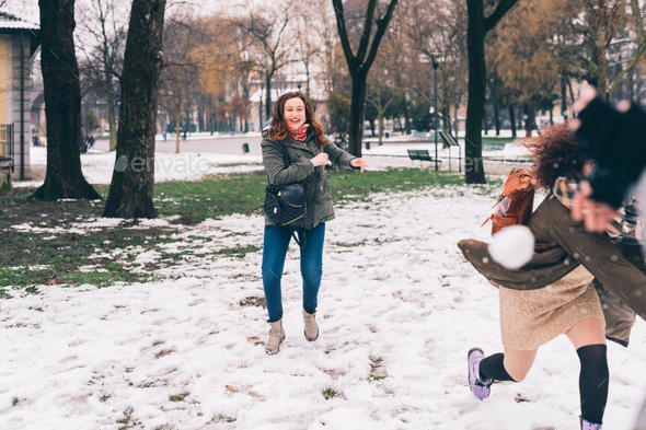 two young women multiethnic playing snow ball fight