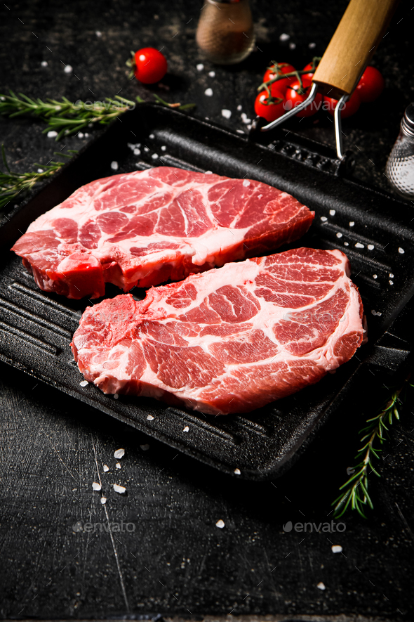 Raw pork steak in a frying pan with bay leaves and rosemary. Stock Photo by Artem_ka2