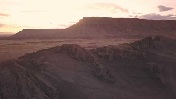 Flying over dunes at sunset with people on motorcylces in the distance alt