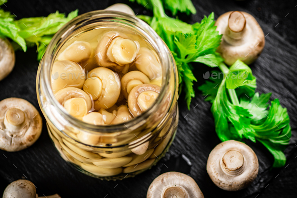 Pickled mushrooms in a jar with greens on a stone board. Stock Photo by ...