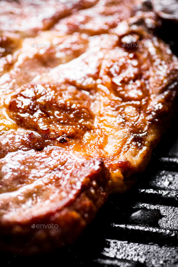 Grilled pork steak in a frying pan. Macro background. Stock Photo by