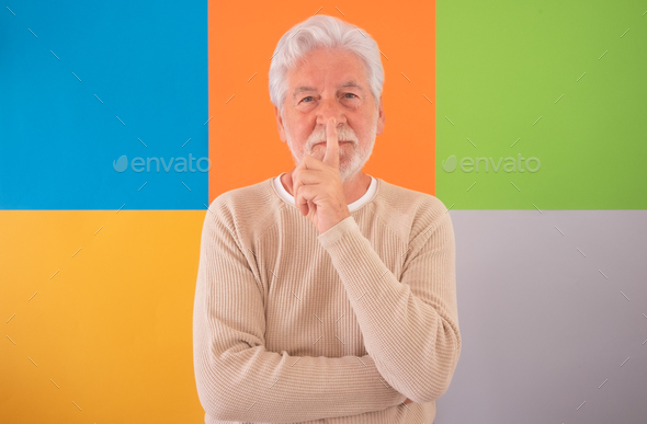 Shut up. Silence please. Adult handsome senior man looking at camera standing on colorful background