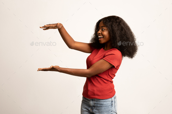 Excited Black Female Holding Big Invisible Object In Her Hands - Stock Photo - Images