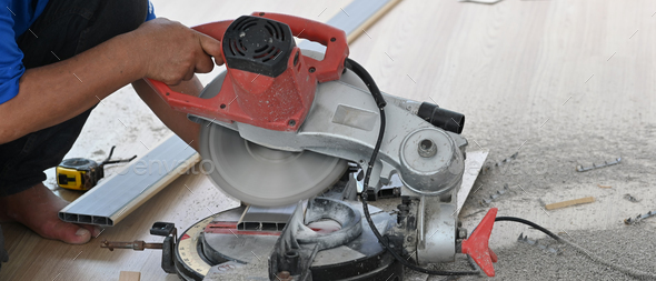 Cabinet maker cutting wood board with electric circular saw at woodworking.