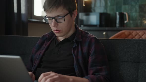 A Young Man with Glasses Works in a Coworking Space