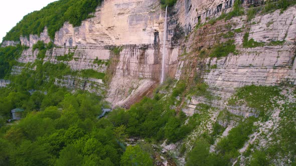 Beautiful Scenery of a Huge Cliff and Long Waterfall on It Aerial Shot alt
