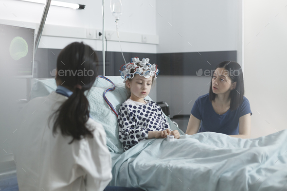 Clinic pediatric medic analyzing EEG scan results of sick little child while in pediatric ward