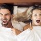 Young Woman And Her Man Showing Surprise And Looking At Camera While Lying In Bed Under Blanket - PhotoDune Item for Sale