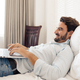 Happy Handsome Man Using Laptop. Lying On Bed In Bedroom. - PhotoDune Item for Sale