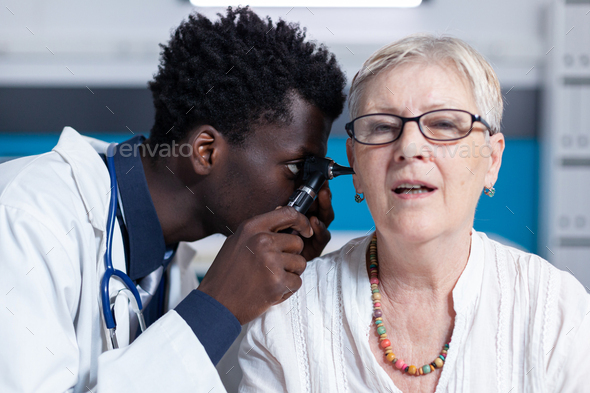 Healthcare facility otologist checking internal ear infection or illness using otoscope