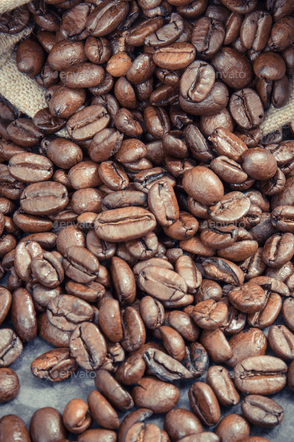 Heap of dark roasted fragrant coffee beans in jute bag