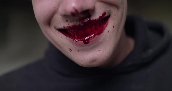 Close Portrait of a Man with Bloodied Mouth Smiles at the Camera alt