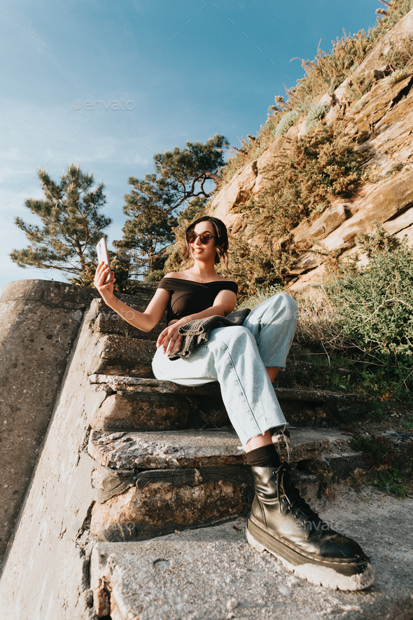 Portrait of a modern young woman sitting on stairs with military boots