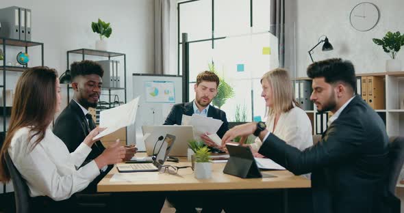Team of Coworkers Sitting Together at Workplace and Get Equainted with Financial Reports alt
