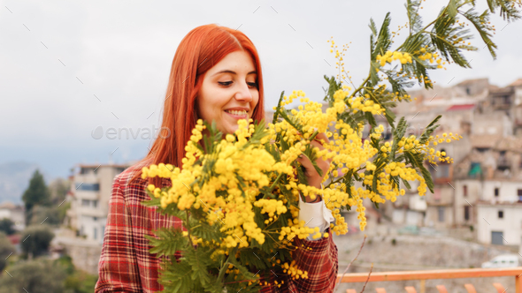 Red hair woman with mimosa flowers in her hand. Womans Day