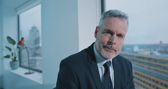 Close up of a businessman with blue eyes looking straight to the camera alt