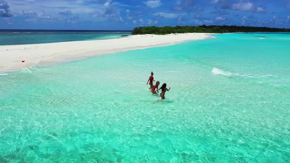 Young happy ladies on photoshoot spending quality time at the beach on sunny blue and white sand background alt