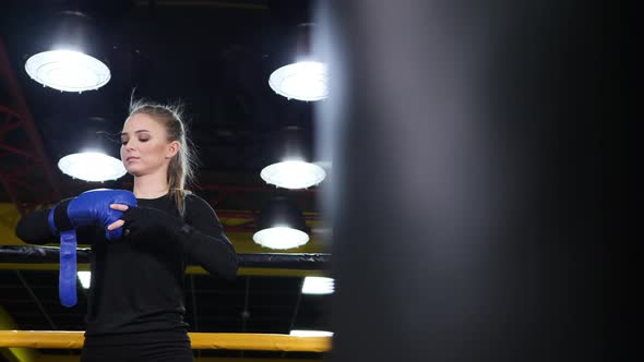 Athletic Young Woman Puts on Boxing Gloves in the Ring Before Training