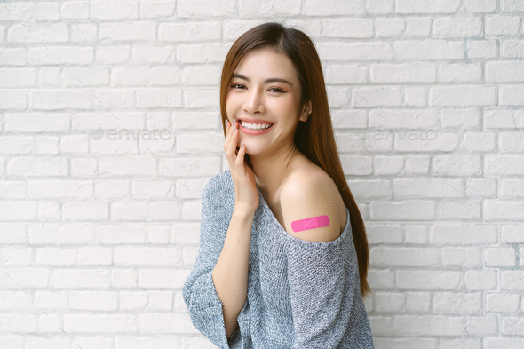 Asian woman wearing off shoulder sweater sleeve showing arm with adhesive bandage plaster covid-19