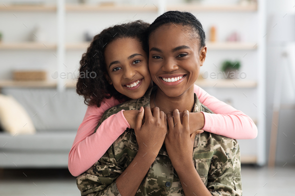 Portrait of happy black teen girl hugging her mother soldier
