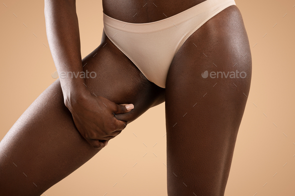 Unrecognizable black woman in panties showing excessive fat on