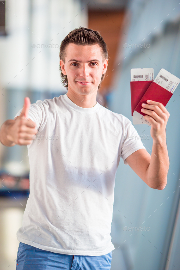 Young man with passports and boarding passes in airport - Stock Photo - Images