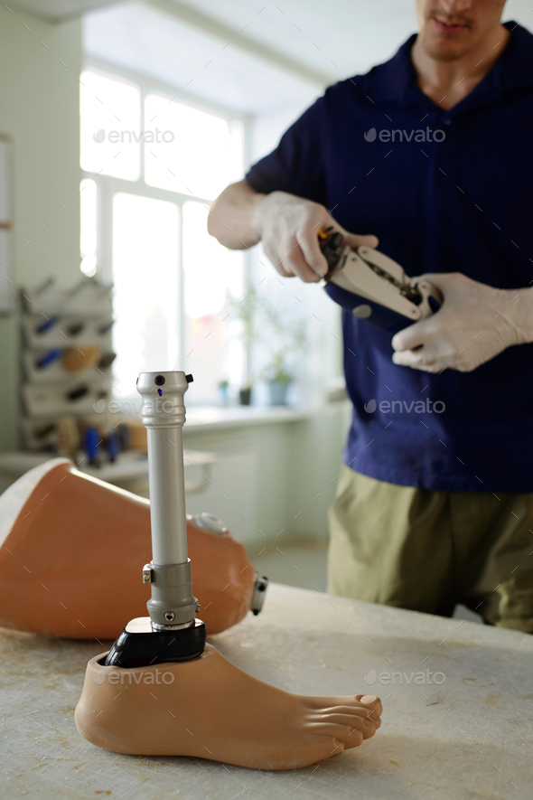 Manual worker standing in front of table with parts of leg prosthesis