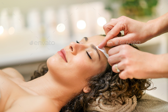 Master waxing eyebrow of relaxed client in beauty studio