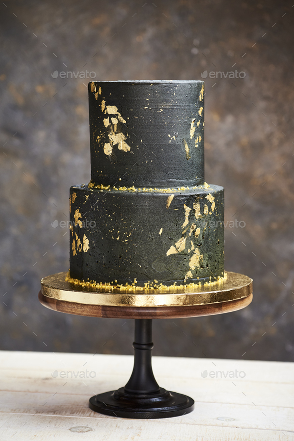 elegant black and gold wedding cake with a modern and luxurious boho look on a wood base - Stock Photo - Images