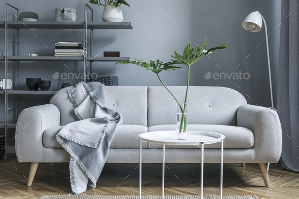 Stylish nordic living room with design grey sofa, coffee table, white lamp.