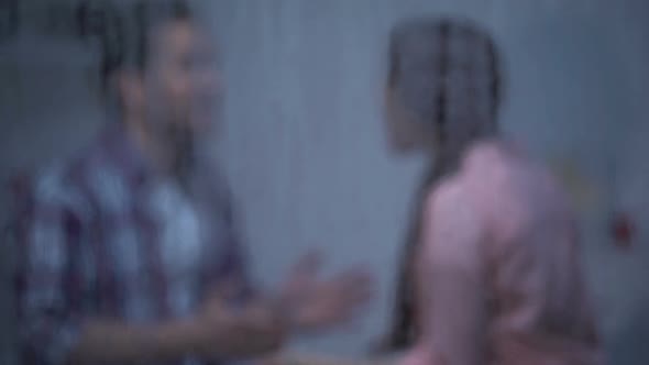 Angry Man and Woman Quarrelling at Home Behind Rainy Window alt